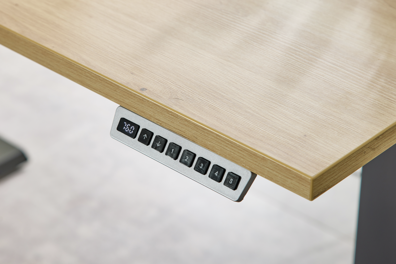 Nahaufnahme eines höhenverstellbaren Schreibtisches mit digitalem Bedienfeld an der Tischkante.