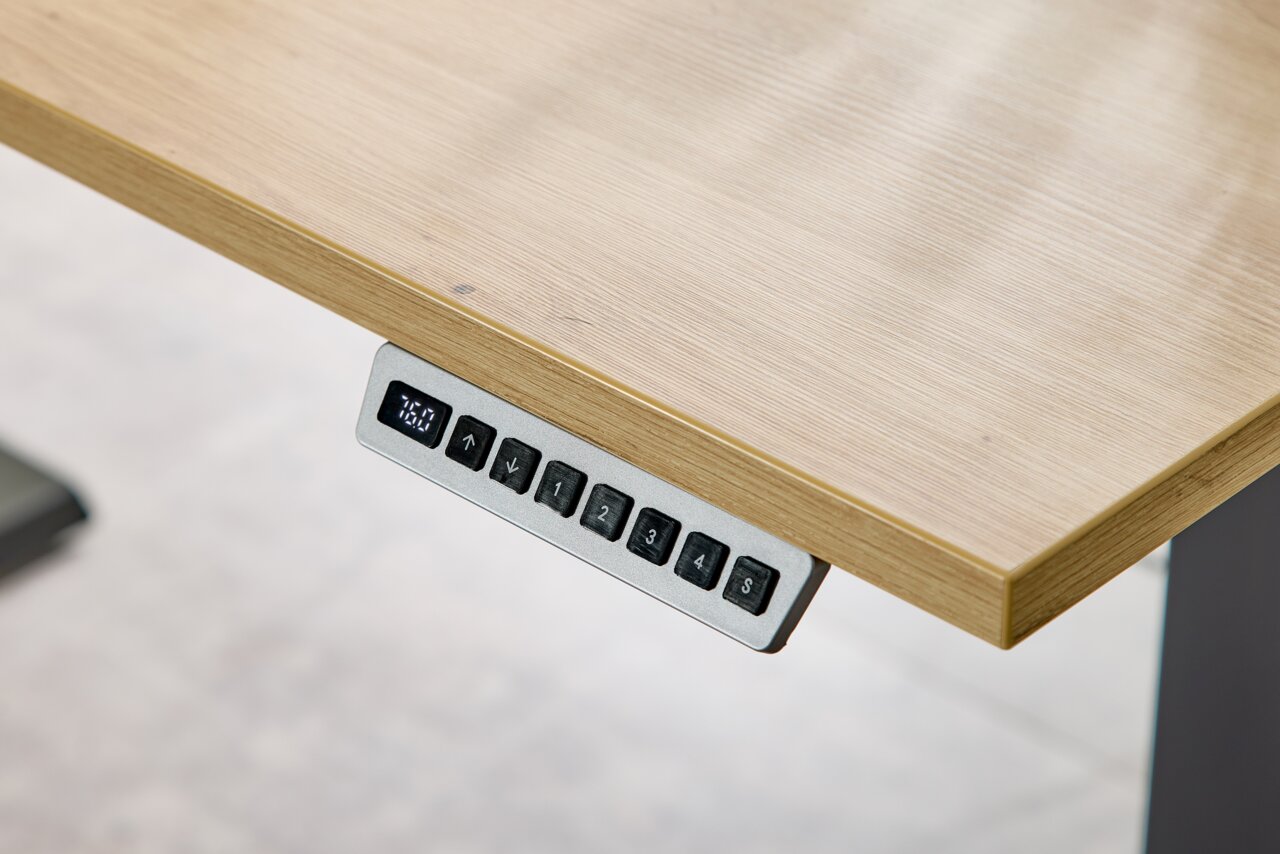 Nahaufnahme eines höhenverstellbaren Schreibtisches mit digitalem Bedienfeld an der Tischkante.