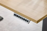 Nahaufnahme eines höhenverstellbaren Schreibtisches mit digitalem Bedienfeld an der Tischkante.