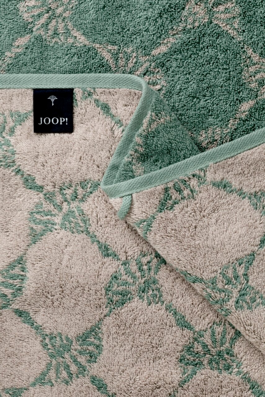 Nahaufnahme eines Handtuchs mit grünem und beigem Muster, Markenetikett 'JOOP!' sichtbar.