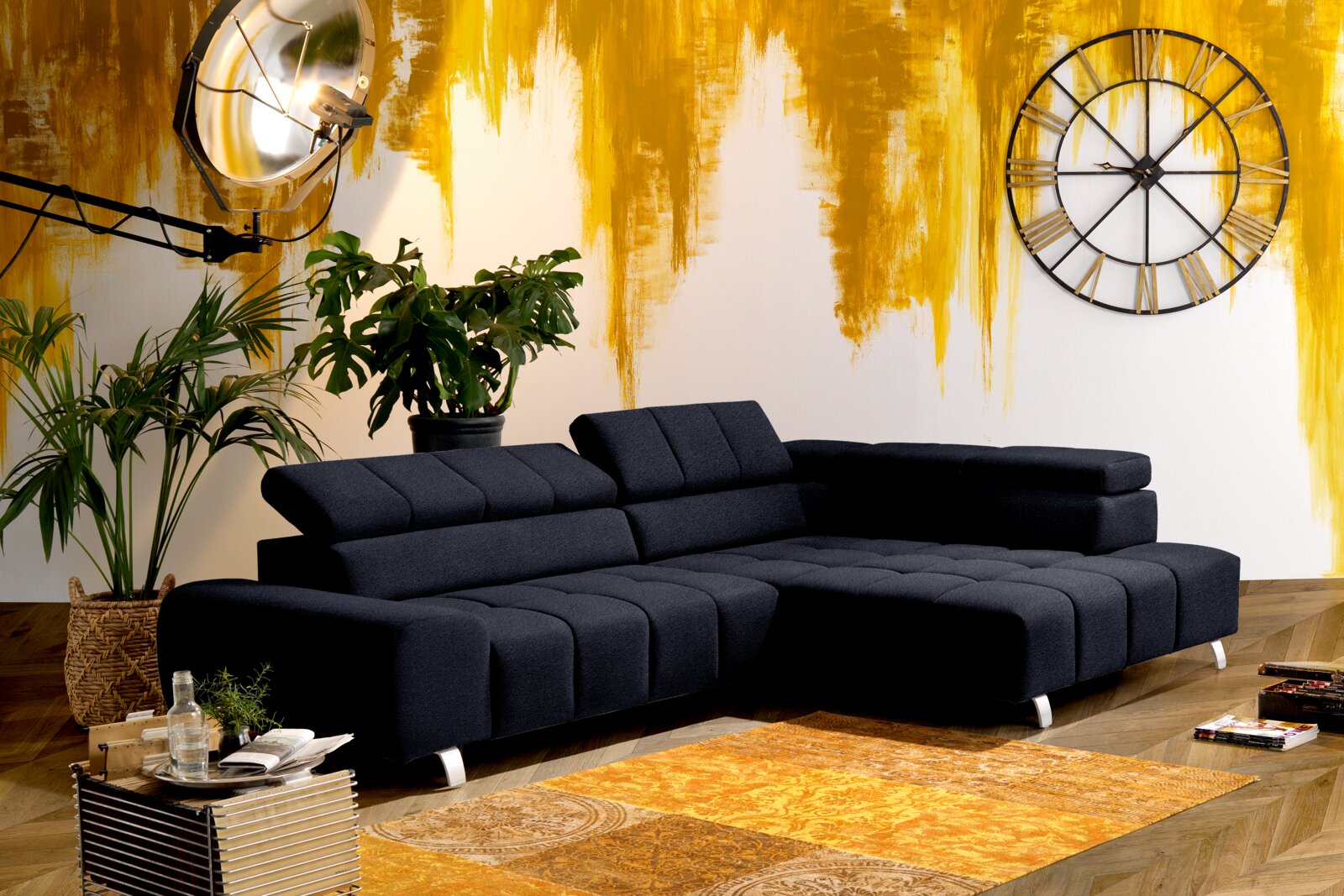 Moderne schwarze Rundecke mit Ottomane rechts, in einem stilvoll eingerichteten Raum mit gelber Akzentwand, Pflanzen und großer Wanduhr. Perspektive von vorne links.