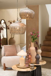 Zwei dekorative Hängeleuchten mit orientalischem Muster, von der Seite betrachtet, hängen über einem stilvoll eingerichteten Wohnzimmer mit modernen Möbeln und Dekorationen.