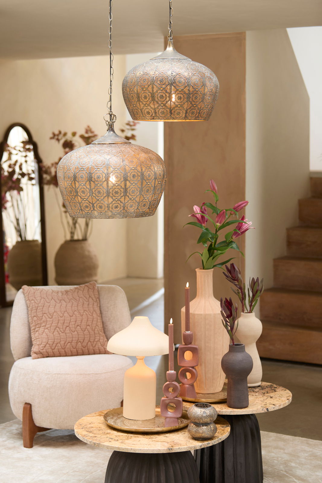 Zwei dekorative Hängeleuchten mit orientalischem Muster, von der Seite betrachtet, hängen über einem stilvoll eingerichteten Wohnzimmer mit modernen Möbeln und Dekorationen.