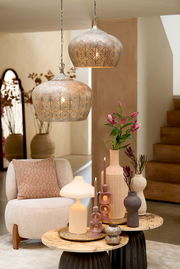 Zwei dekorative Hängeleuchten mit orientalischem Muster, von der Seite betrachtet, hängen über einem stilvoll eingerichteten Wohnzimmer mit modernen Möbeln und Dekorationen.