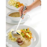 Hand hält einen Edelstahl-Gießlöffel PROFI PLUS, der Soße über ein Gericht mit Fleisch, Nudeln und Gemüse gießt, aus der Vogelperspektive.