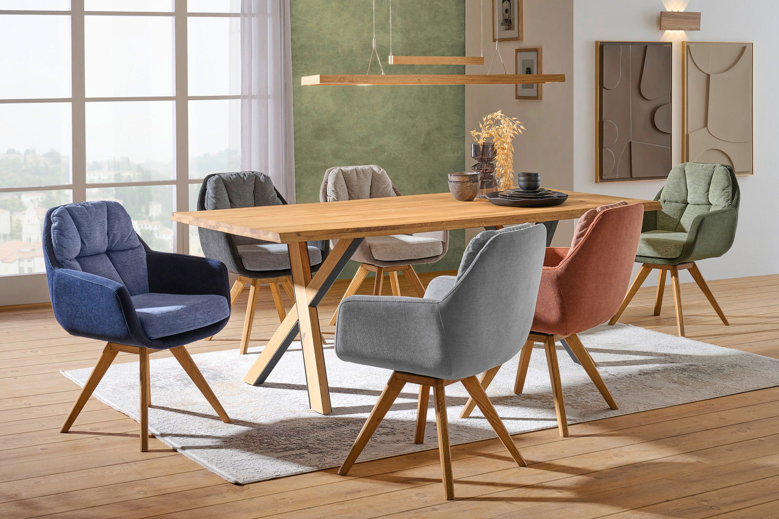 Moderner Esstisch aus Holz mit sechs farbigen Stühlen in einem stilvoll eingerichteten Raum, seitliche Perspektive.