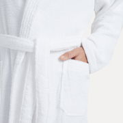 Nahaufnahme eines weißen Bademantels mit Schalkragen in Größe XL, mit einer Hand in der Tasche.