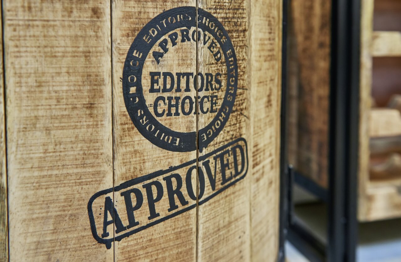 Close-up van een rustieke houten drankkast met de stempels 'Editor's Choice' en 'Approved' op het oppervlak.
