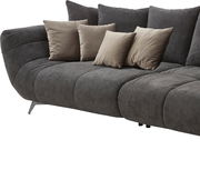 Großes, modernes Sofa in dunklem Grau mit mehreren beigen Kissen, seitliche Perspektive