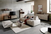 Modernes Wohnzimmer mit einem großen, beigen Big-Sofa, dekoriert mit gemusterten Kissen und einer roten Decke, aus der Perspektive von vorne betrachtet.