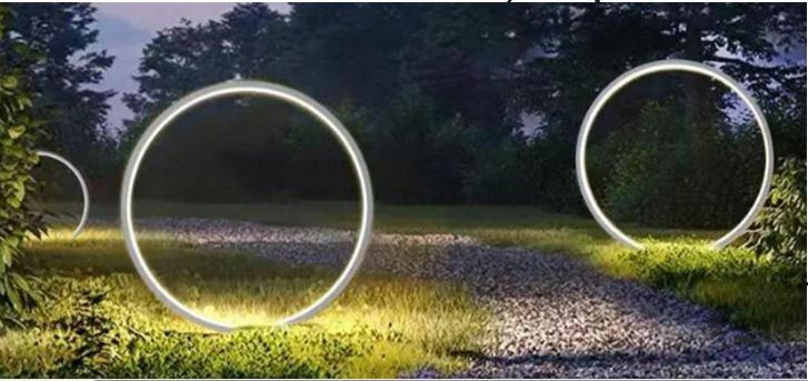 Erdspießleuchte ZIRKULU in einem Garten bei Dämmerung, leuchtende Ringe entlang eines Kieswegs, seitliche Perspektive