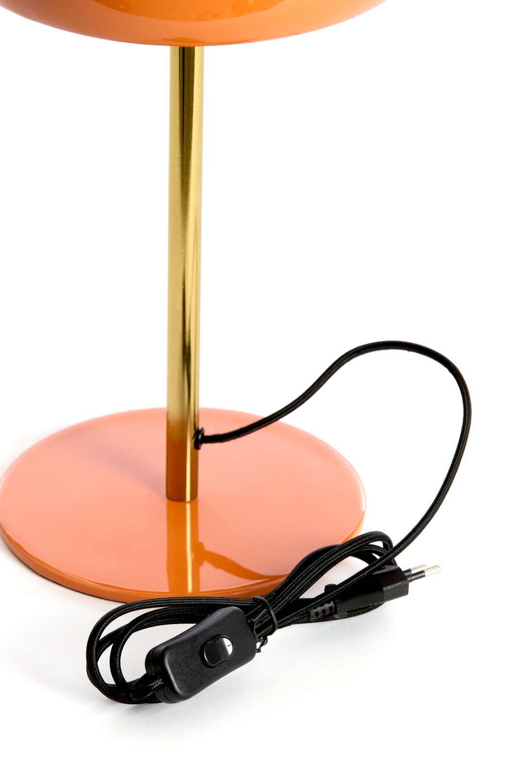 Nahaufnahme einer Tischleuchte mit orangefarbenem Sockel und goldfarbenem Ständer, inklusive schwarzem Kabel mit Schalter.