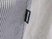 Nahaufnahme eines grauen, gerippten Stoffes mit einem schwarzen Etikett, auf dem 'CARRYHOME' steht, seitliche Perspektive.