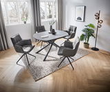 Moderner Esstisch mit ovaler grauer Tischplatte und schwarzen Metallbeinen, umgeben von vier gepolsterten Stühlen in einem hellen Raum mit großen Fenstern, aus der Vogelperspektive.