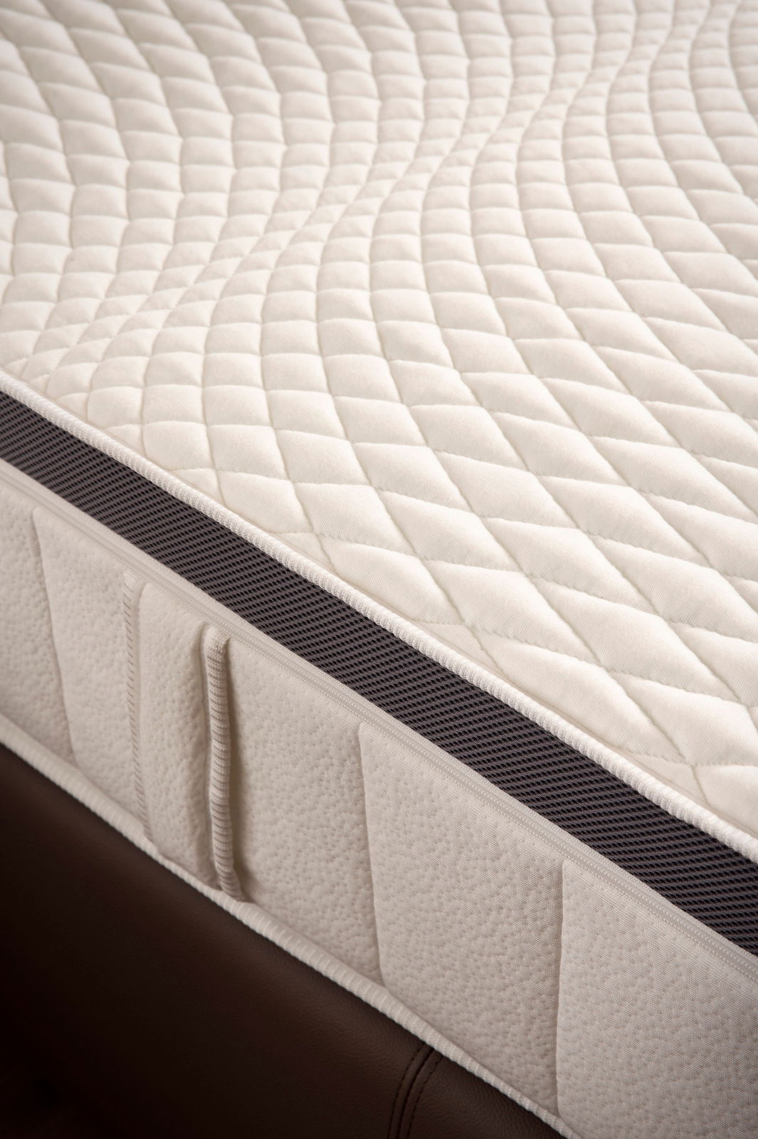 Nahaufnahme einer Matratze mit gestepptem Bezug und seitlichem Belüftungsstreifen, perspektivisch von oben fotografiert.