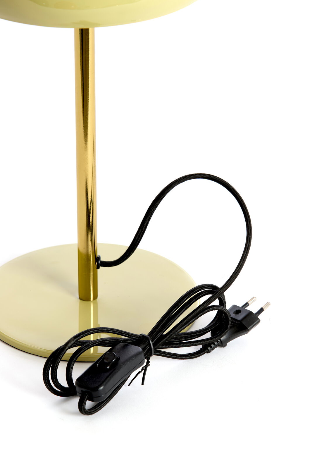 Nahaufnahme einer Tischleuchte mit einem goldenen Ständer und einem runden, hellgrünen Sockel. Ein schwarzes Kabel mit Schalter und Stecker ist sichtbar.
