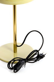 Nahaufnahme einer Tischleuchte mit einem goldenen Ständer und einem runden, hellgrünen Sockel. Ein schwarzes Kabel mit Schalter und Stecker ist sichtbar.