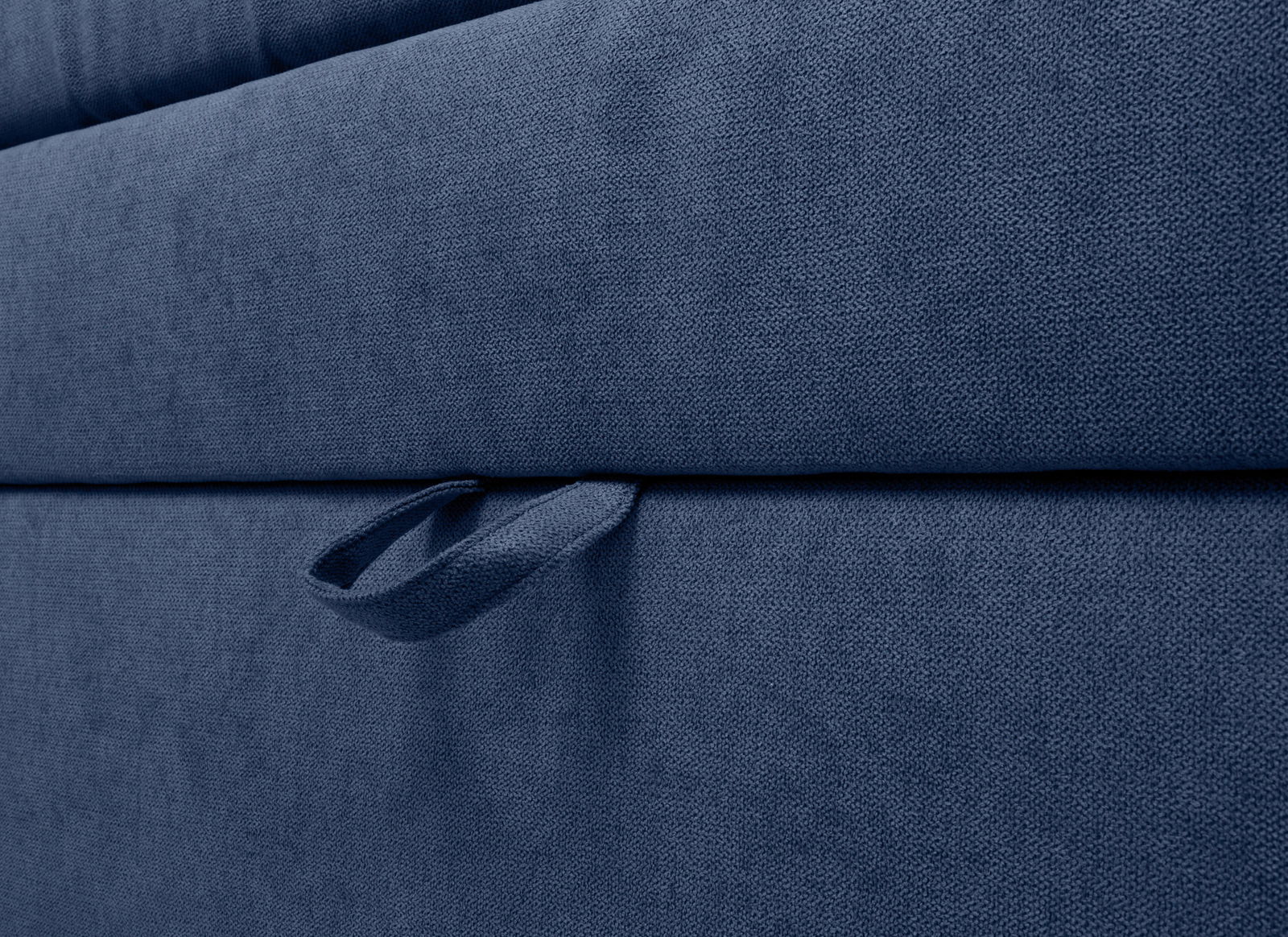 Nahaufnahme eines blauen Boxspringbetts mit Stoffstruktur und Griff, seitliche Perspektive