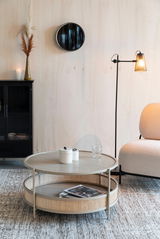 Runder Couchtisch mit zwei Ebenen, aus hellem Holz und Rattan, in einem modernen Wohnzimmer mit seitlicher Perspektive.