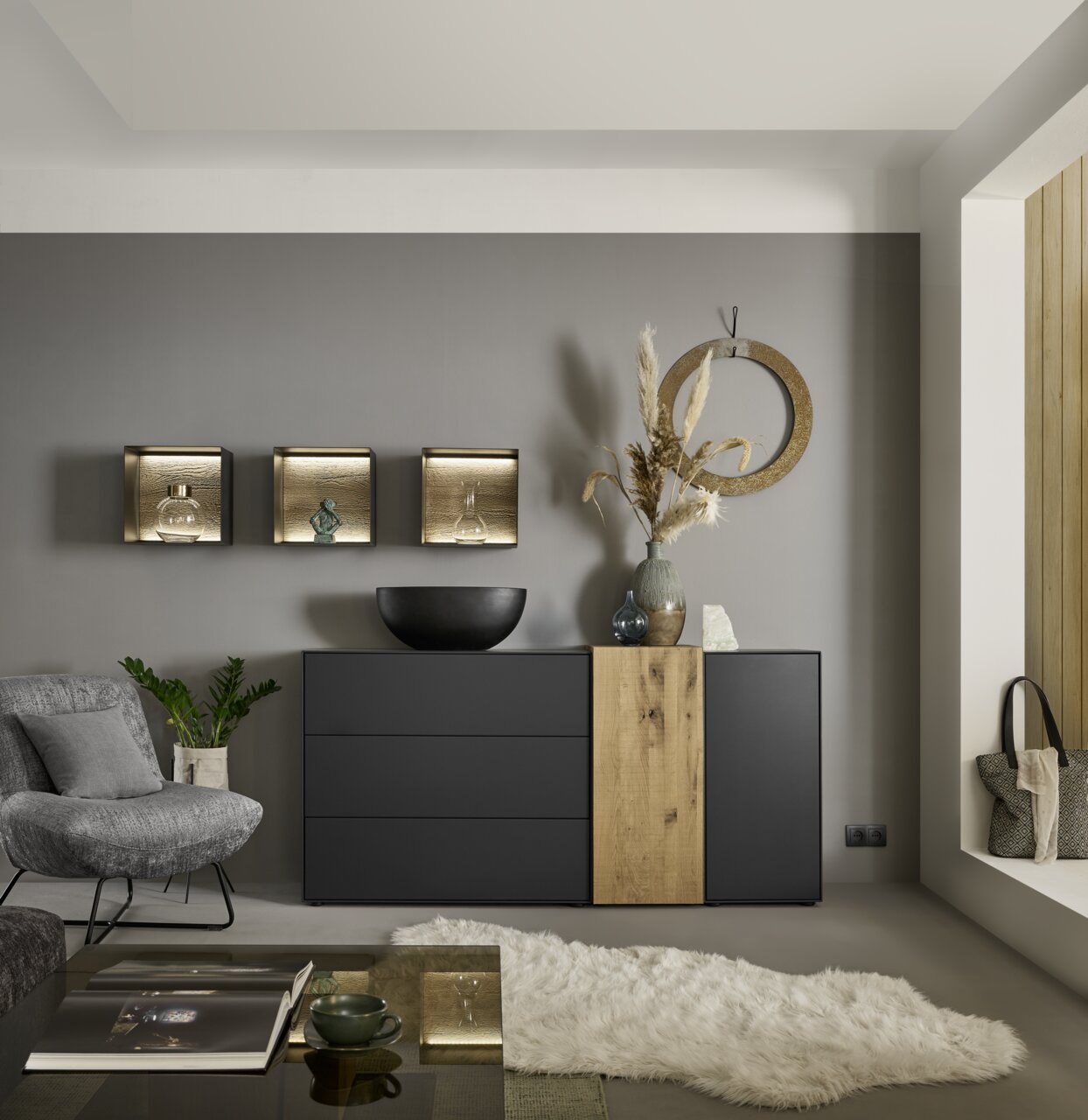 Musterring Dressoir TREVIO Modernes Sideboard in Schwarz mit Holzelement, dekoriert mit Vasen und Schalen, in einem stilvollen Wohnzimmer. Perspektive von vorne.