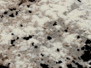 Nahaufnahme eines Designer Teppichs mit flauschiger Textur in Creme-, Beige- und Schwarztönen, aus der Vogelperspektive fotografiert.