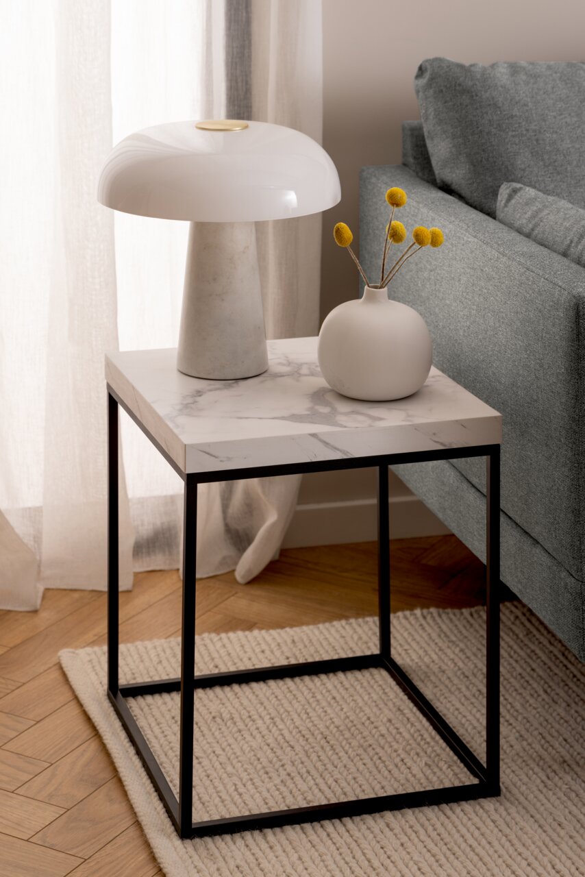 Moderner Couchtisch mit Marmoroptik-Oberfläche und schwarzem Metallgestell, seitliche Perspektive.