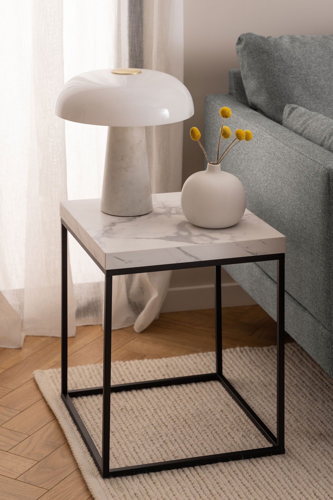Moderner Couchtisch mit Marmoroptik-Oberfläche und schwarzem Metallgestell, seitliche Perspektive.