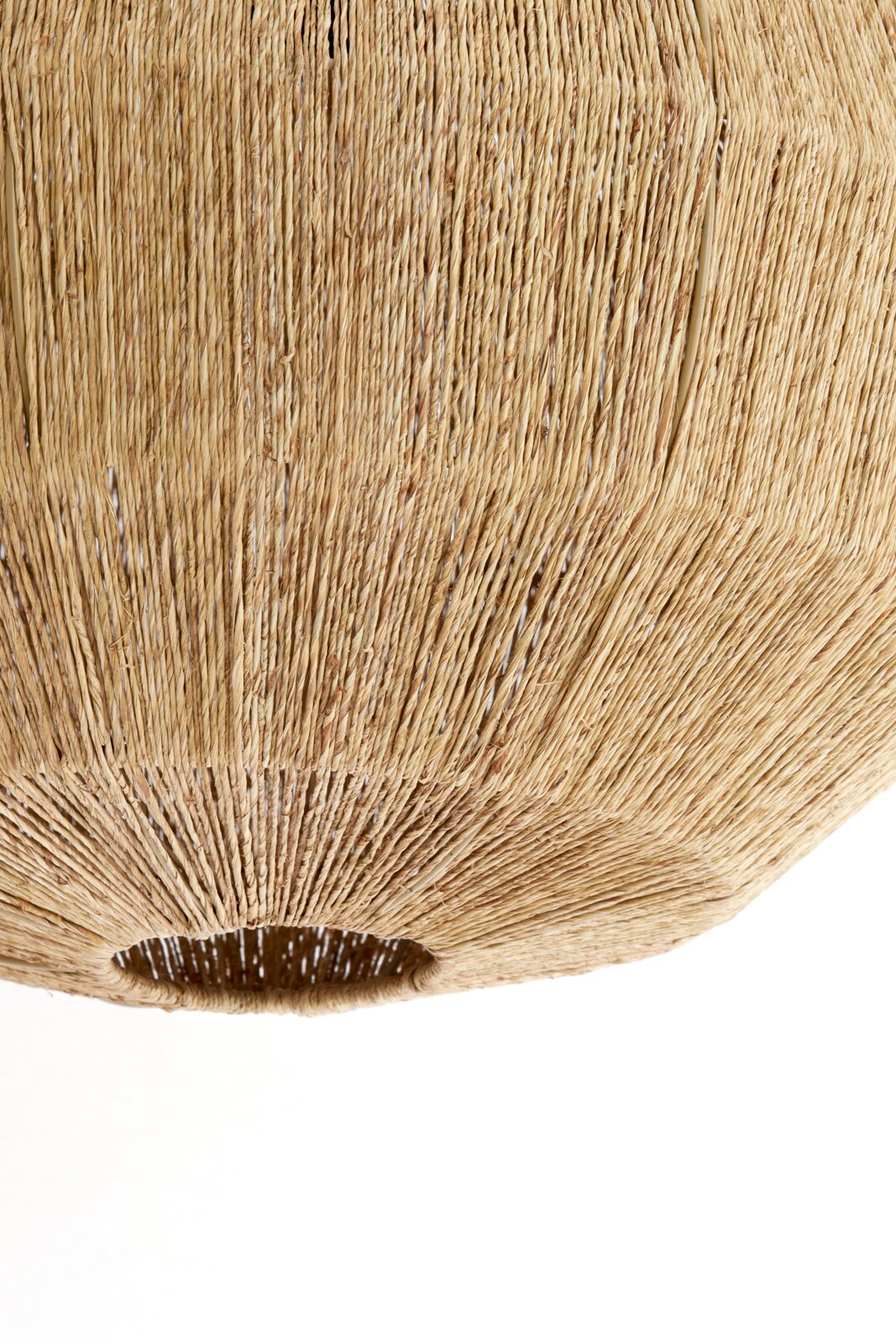 Close-up van een hanglamp van gevlochten natuurmateriaal, gezien van onderaf.
