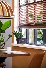 Moderne Uhr auf einer Fensterbank neben einer Pflanze, seitliche Perspektive