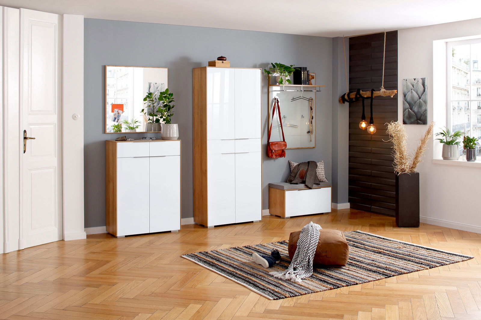 Moderne Garderobeneinrichtung mit Schuhschrank, Spiegel, Sitzbank und Garderobenpaneel in einem hellen Raum mit Holzboden, aus der Perspektive von vorne betrachtet.