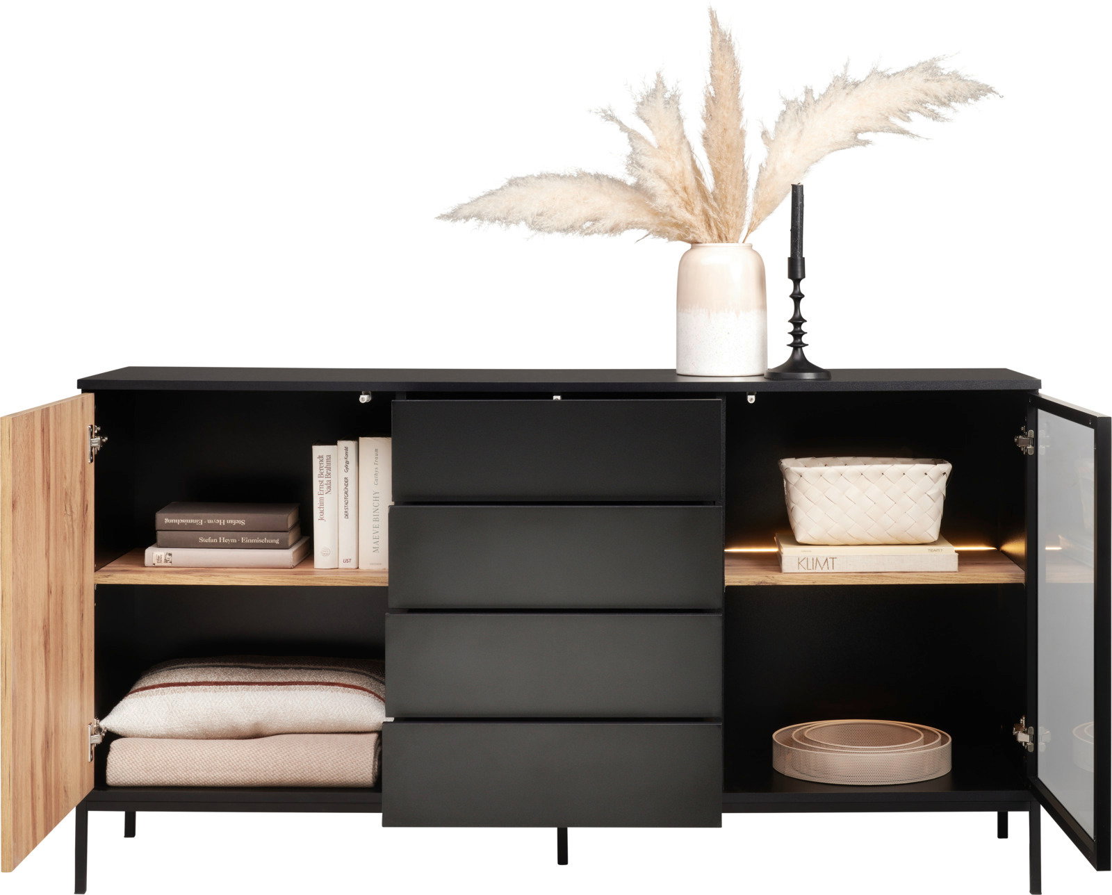 Modernes Sideboard mit schwarzer Front, offenen Türen und Schubladen, dekoriert mit Büchern, Körben und einer Vase mit Pampasgras, frontal betrachtet.