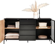 Modernes Sideboard mit schwarzer Front, offenen Türen und Schubladen, dekoriert mit Büchern, Körben und einer Vase mit Pampasgras, frontal betrachtet.