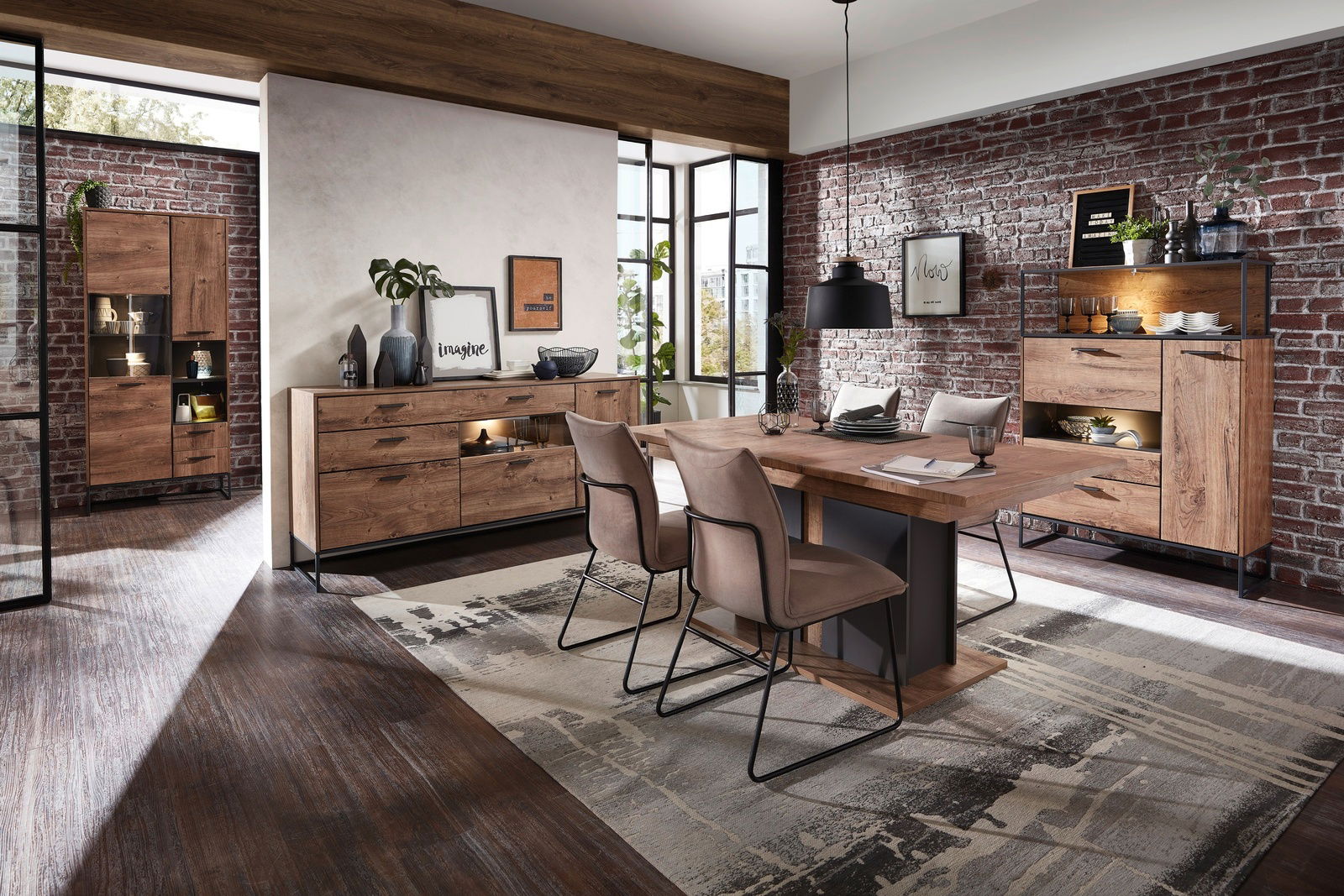 Moderne Esszimmer-Einrichtung mit Holzmöbeln, bestehend aus einem Esstisch, Sideboard und Vitrine, in einem Raum mit Backsteinwand und großen Fenstern. Perspektive von vorne.