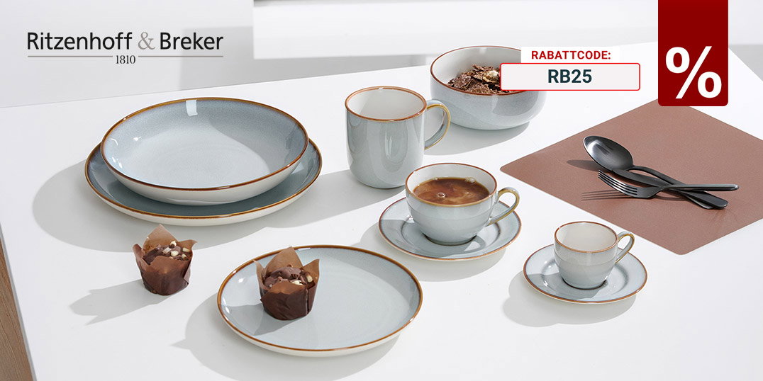 Graues Keramik-Geschirr mit Tassen, Schalen und Tellern auf weißem Tisch, dazu Kaffee und Muffins.