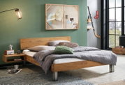 Modernes Doppelbett aus massivem Holz mit niedrigem Rahmen und Metallfüßen, im Industrial-Schlafzimmer mit grüner Wand und großer Fensterfront, perspektivisch schräg von vorne rechts aufgenommen