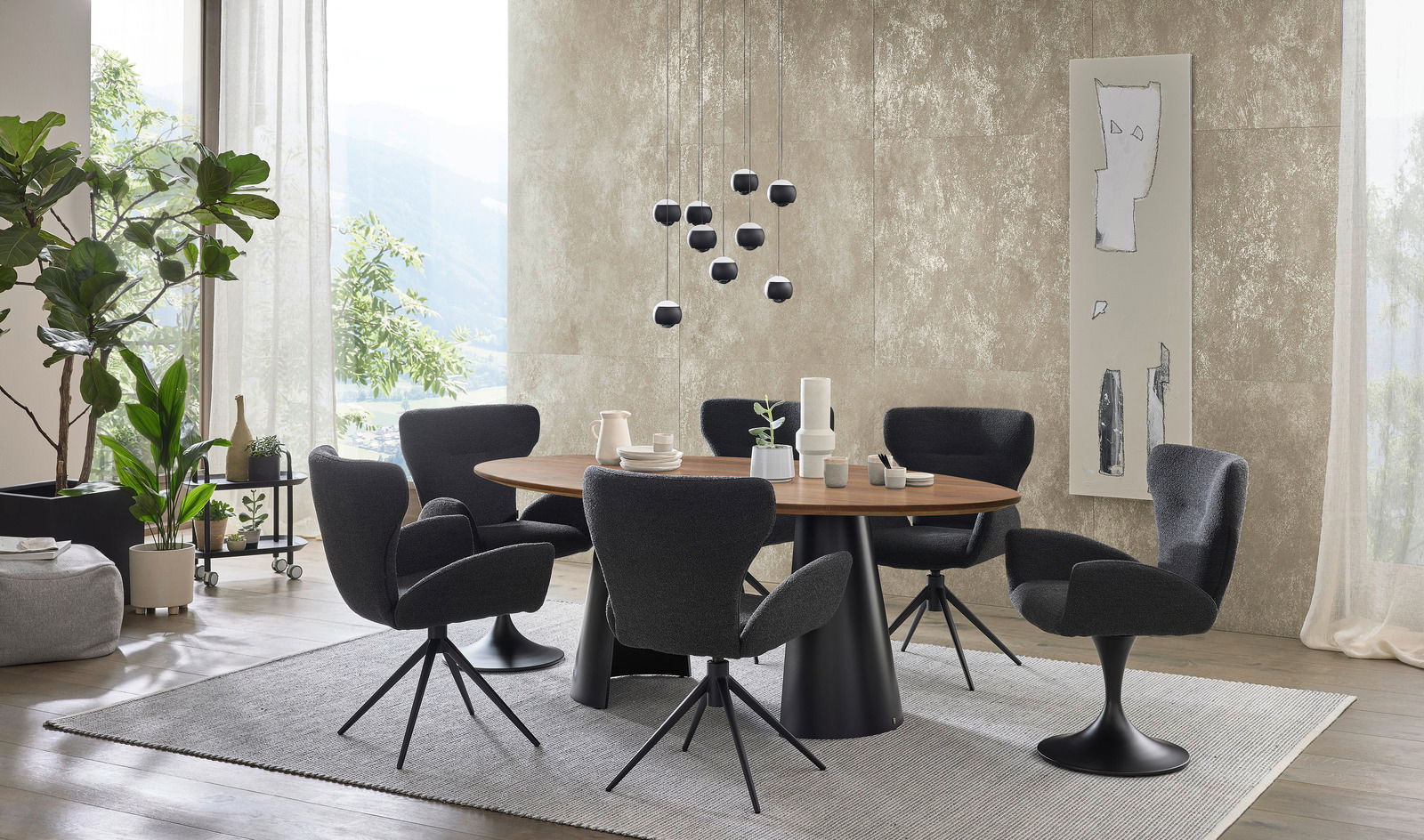 Moderner Essbereich mit rundem Holztisch und schwarzen Armlehnstühlen, umgeben von Pflanzen und dekorativen Elementen, seitliche Perspektive.