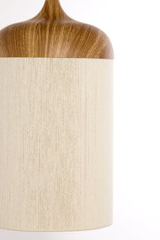 Zylindrische Tischlampe mit beigem Stoffschirm und Holzoptik-Kopfteil, frontale Nahaufnahme vor weißem Hintergrund