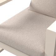 Close-up van een loungestoel met een beige stoffen bekleding en een crèmekleurig frame, gezien van bovenaf.