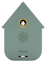 Vorderansicht einer modernen, grünlichen Soundbox in Form eines Hauses mit einem kleinen Vogel in einem runden Fenster und Lautsprecherlöchern darunter.