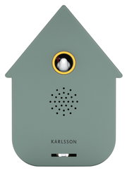 Vorderansicht einer modernen, grünlichen Soundbox in Form eines Hauses mit einem kleinen Vogel in einem runden Fenster und Lautsprecherlöchern darunter.