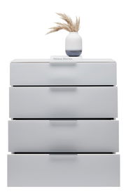 Weiße Schubkastenkommode mit vier Schubladen, darauf eine Vase mit getrockneten Gräsern und ein Buch, frontale Perspektive.