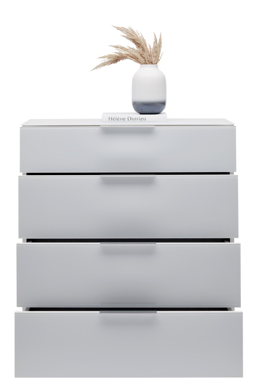 Weiße Schubkastenkommode mit vier Schubladen, darauf eine Vase mit getrockneten Gräsern und ein Buch, frontale Perspektive.