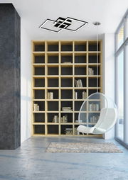 Moderne LED-Deckenleuchte in geometrischem Design, an der Decke eines stilvollen Wohnzimmers mit Bücherregal und Hängesessel montiert, aus der Perspektive des Raumes betrachtet.