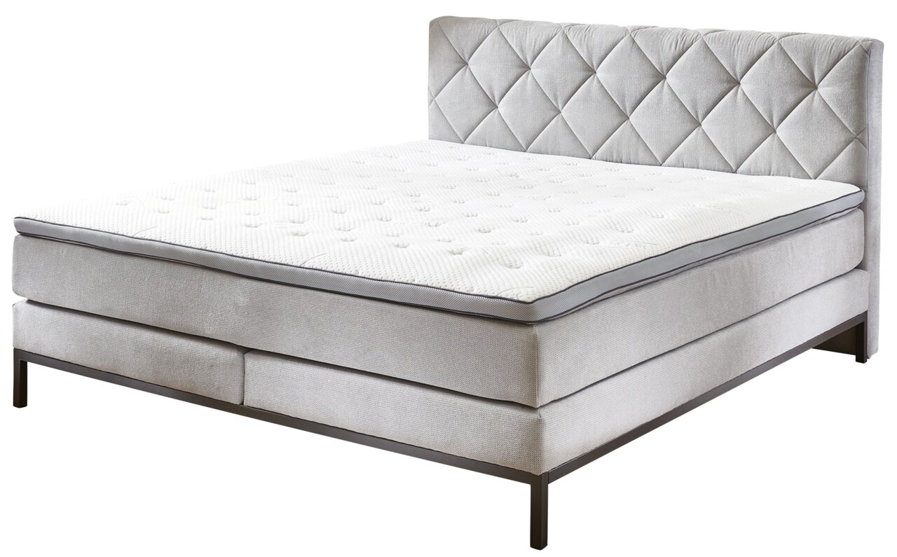 Boxspringbed in zijaanzicht met gestoffeerd hoofdeinde en elegante stiksels