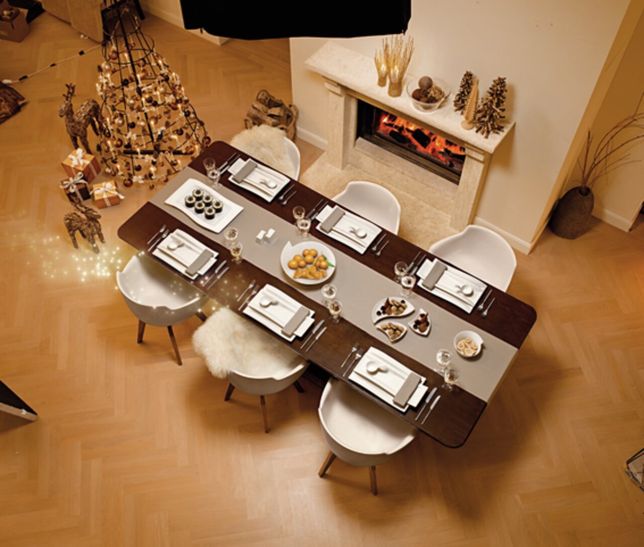 Villeroy & Boch Tafelbestek, 30-delig NEW WAVE Een elegante eettafel met een feestelijke tafelschikking, gezien vanuit vogelperspectief, gedecoreerd met het 30-delige NewWave-bestek, omringd door stijlvolle kerstversieringen en een open haard op de achtergrond.