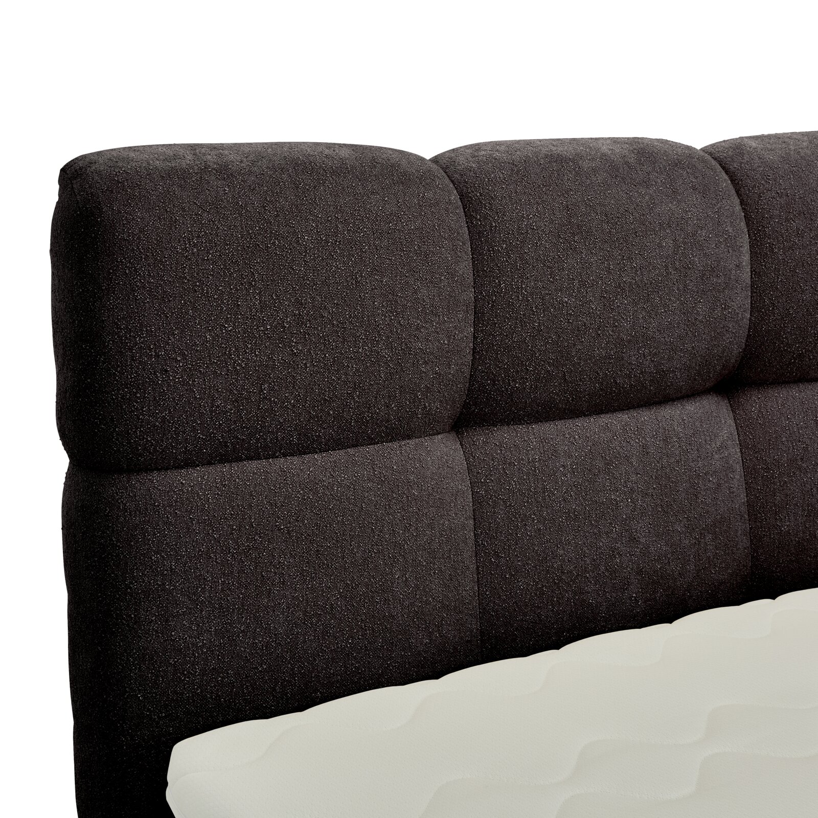 Nahaufnahme eines gepolsterten, dunkelgrauen Boxbett-Kopfteil mit sichtbarer Matratze in Seitenansicht.