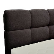 Nahaufnahme eines gepolsterten, dunkelgrauen Boxbett-Kopfteil mit sichtbarer Matratze in Seitenansicht.