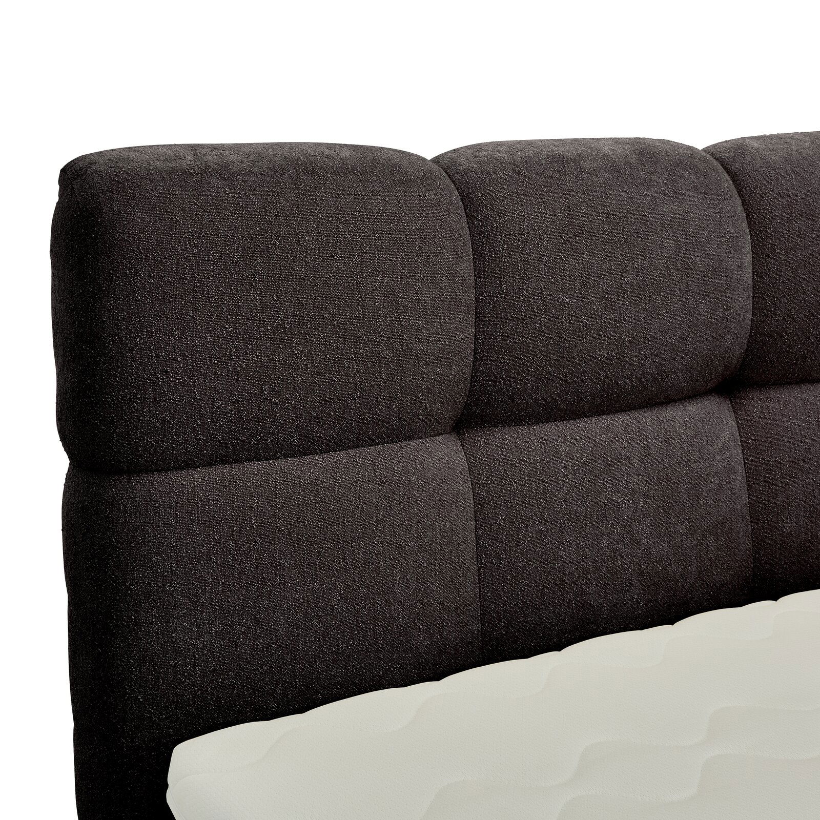 Nahaufnahme eines gepolsterten, dunkelgrauen Boxbett-Kopfteil mit sichtbarer Matratze in Seitenansicht.