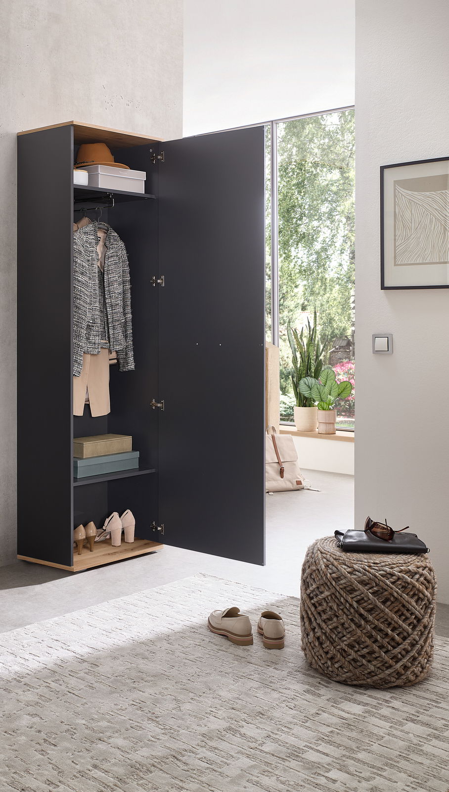 Offener Hochschrank in modernem Design, gefüllt mit Kleidung und Accessoires, in einem hellen Raum mit Blick auf ein Fenster.