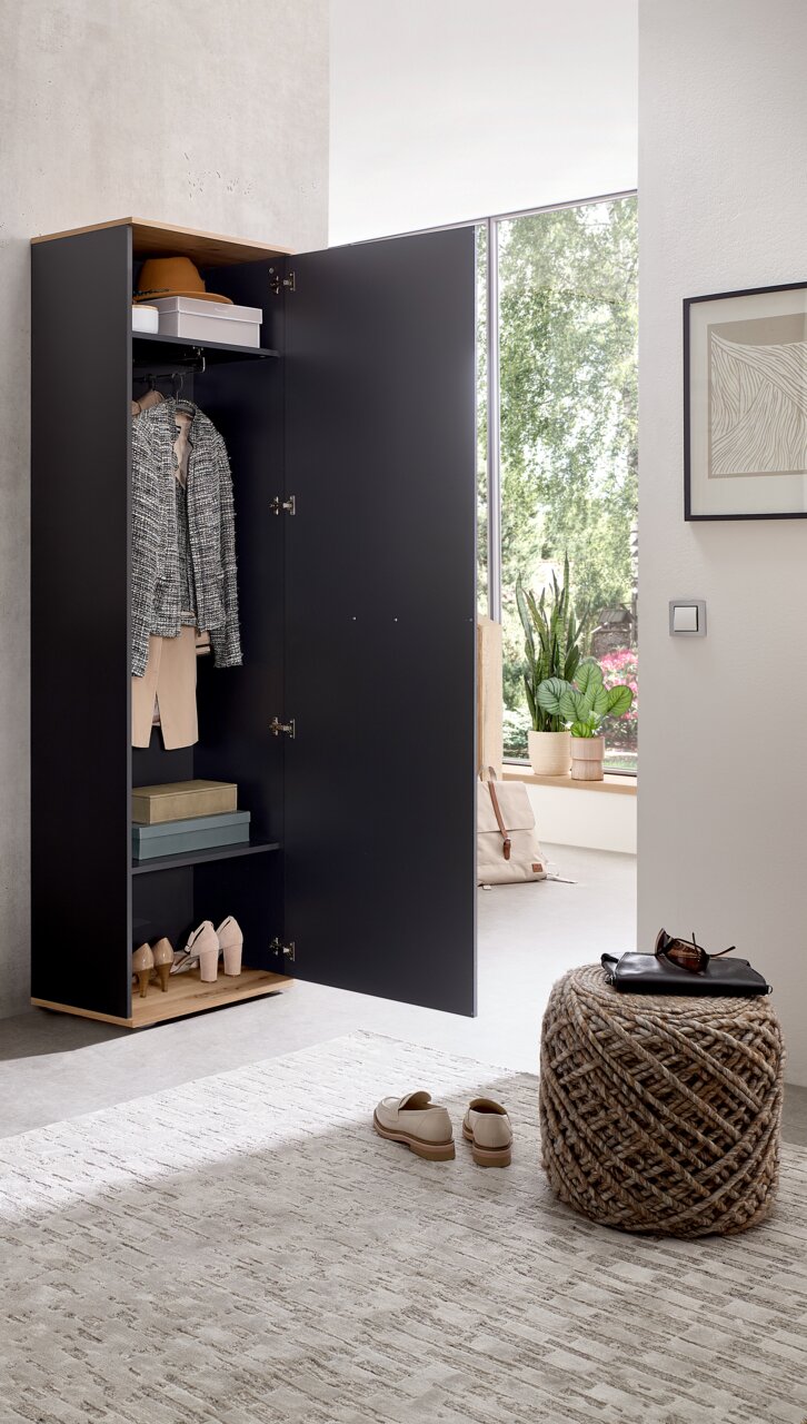 Een open kledingkast in een modern ontwerp, gevuld met kleding en accessoires, in een lichte ruimte met uitzicht op een raam.